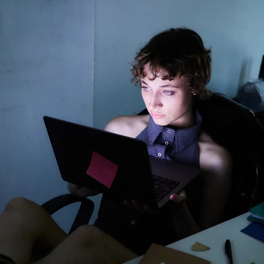 A person lit by a laptop screen, working through an app.